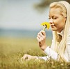 Blond woman smelling dandelions