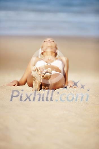 Woman bathing in the sun on a sandy beach Woman bathing in the sun on a sandy beach