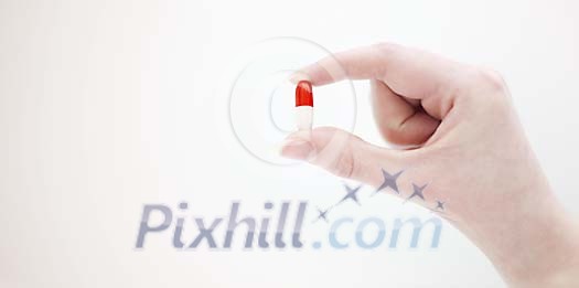 Hand holding a red-white capsule Hand holding a red-white capsule