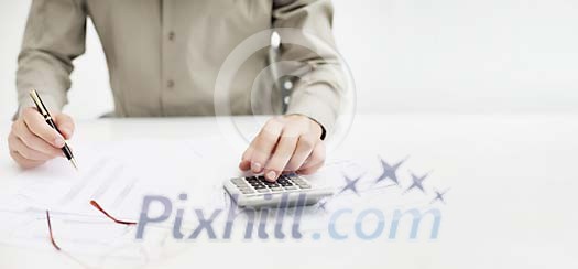 Person working with calculator and reports Person working with calculator and reports