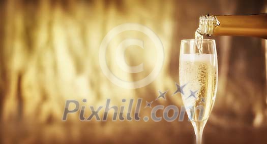 Glass being filled with champagne on a golden background Glass being filled with champagne on a golden background