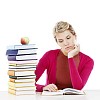 Woman sitting at the desk with a stack of books, reading