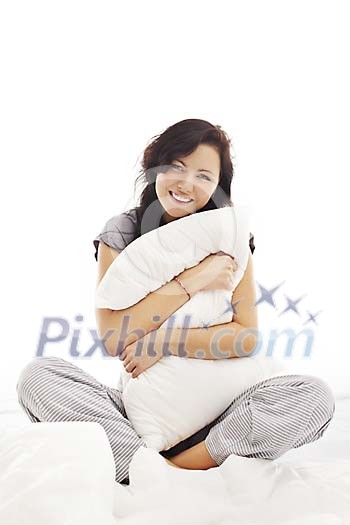 Woman sitting on the bed and holding a pillow Woman sitting on the bed and holding a pillow