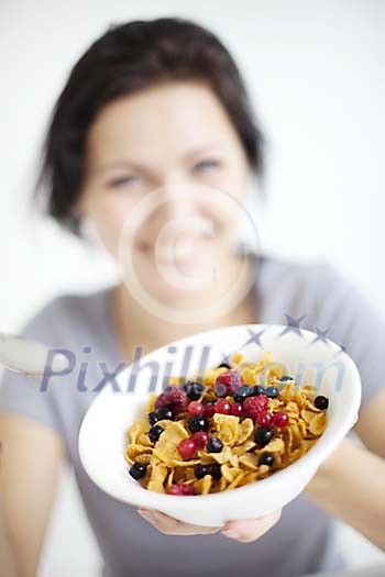 Defocused woman offering a bowl of cornflakes Defocused woman offering a bowl of cornflakes