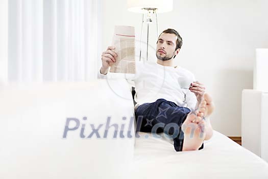 Man sitting on the sofa, reading newspaper Man sitting on the sofa, reading newspaper