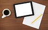 Tablet with paper and cup of coffee on the desk