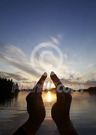 Male hands around setting sun