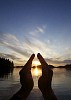 Male hands around setting sun