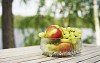 Apples and grapes in a bowl on a sunny table outside