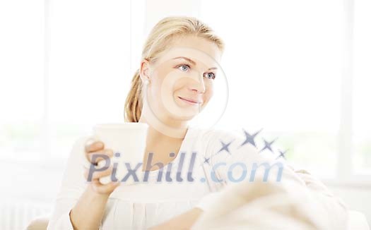 Woman sitting and enjoying a cup of tea in a light surrounding Woman sitting and enjoying a cup of tea in a light surrounding