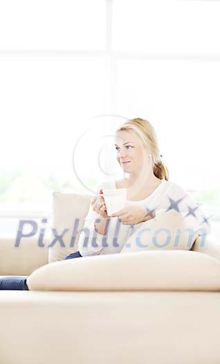 Woman sitting on the couch, having coffee Woman sitting on the couch, having coffee