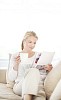 Woman sitting on the couch reading a magazine and drinking coffee