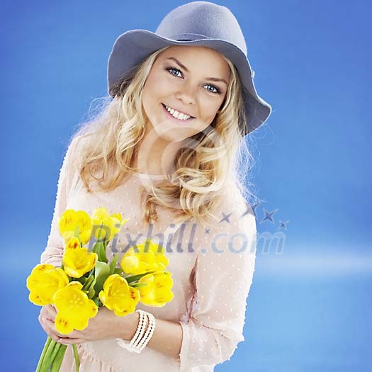 Blonde girl with flowers and summer hat on a deep blue background Blonde girl with flowers and summer hat on a deep blue background
