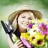 Smiling gardener holding gardening tools and colorful flowers