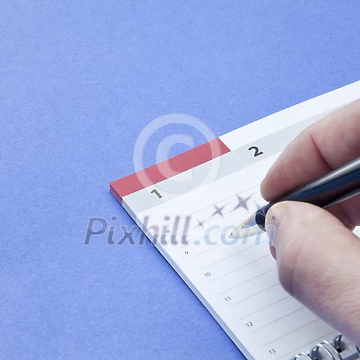 Hand with a pen ready to make a note in the calendar Hand with a pen ready to make a note in the calendar