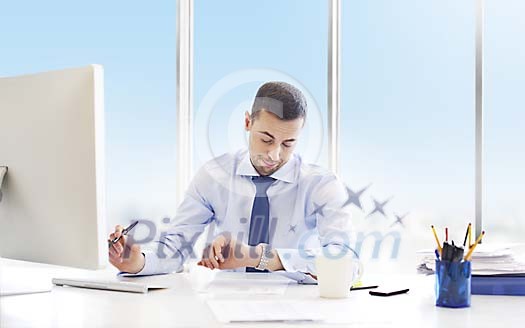 Businessman checking time by his work desk Businessman checking time by his work desk
