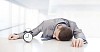 Businessman sleeping at his desk, alarm clock next to him