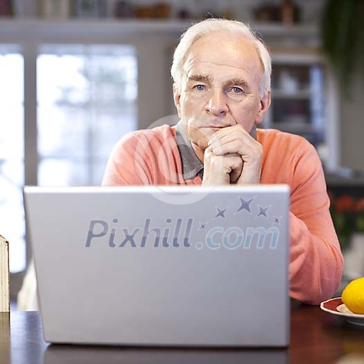 Senior man thinking by laptop at home