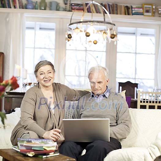 Senior couple sitting on a couch in a light, stylish home Senior couple sitting on a couch in a light, stylish home