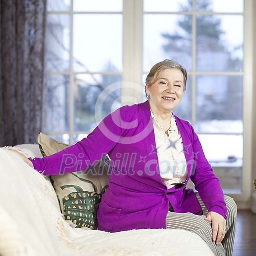 Senior woman sitting on a living room couch Senior woman sitting on a living room couch