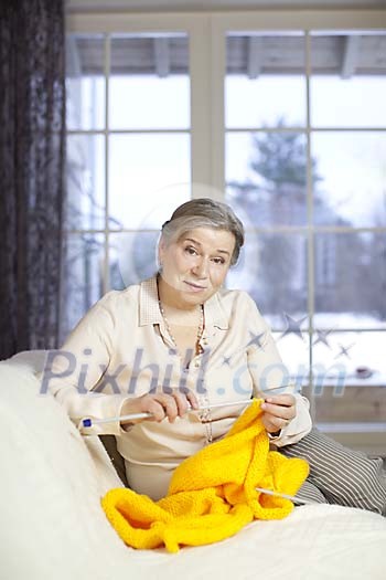 Senior woman knitting on a living room couch Senior woman knitting on a living room couch