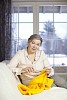 Senior woman knitting on a living room couch