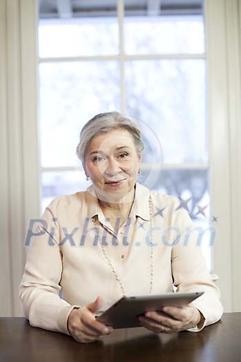Senior woman at home holding iPad Senior woman at home holding iPad