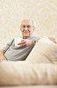 Older male sitting on the sofa, having coffee