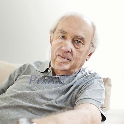 Serious older male sitting on the sofa