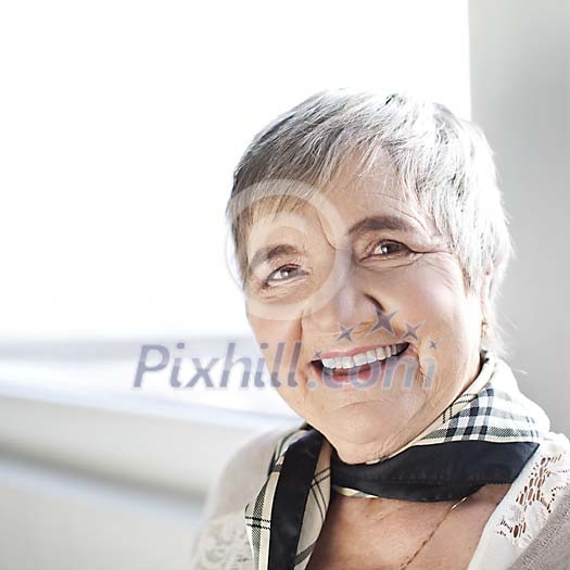 Senior woman smiling by the window Senior woman smiling by the window