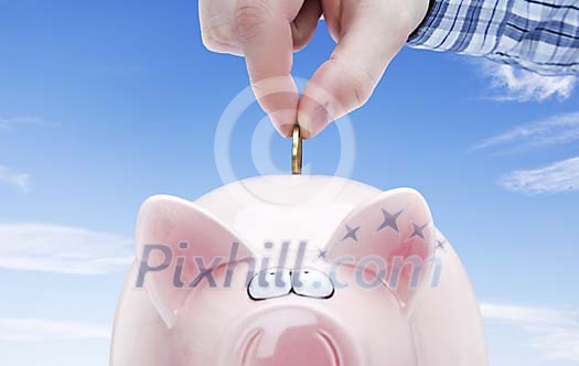 Hand slipping a coin in to the piggy bank Hand slipping a coin in to the piggy bank