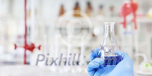 Hand holding a blue solvent in a measuring glass Hand holding a blue solvent in a measuring glass