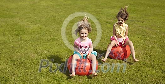 Two girls jumping on the rubber toys Two girls jumping on the rubber toys