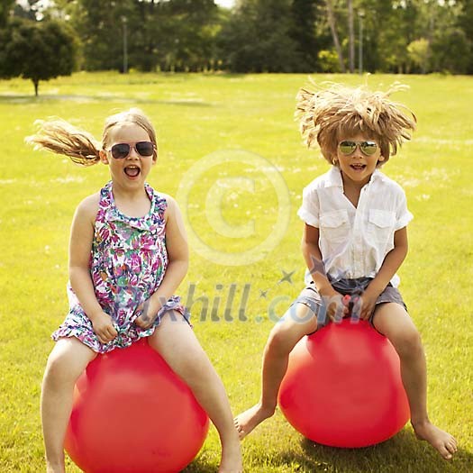 Boy and a girl jumping on the rubber balls Boy and a girl jumping on the rubber balls
