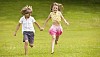 Girl and a boy running on the grass