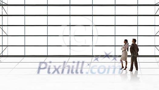 Man and woman standing next to a huge wall of glass Man and woman standing next to a huge wall of glass
