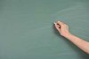 Hand with chalk writing on empty blackboard