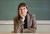 Teacher sitting by her desk and smiling to camera