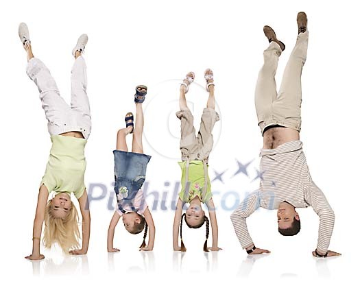 Mom, two daughters and dad doing handstand in white space Mom, two daughters and dad doing handstand in white space