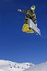 Snowboarder jumping against blue sky