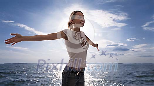 Young woman spreading her arms by the sea