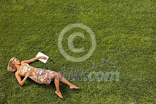 Young woman lying on lawn with a novel Young woman lying on lawn with a novel