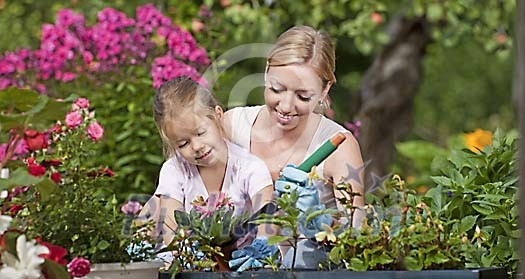Mother and daughter working together in a sunny garden Mother and daughter working together in a sunny garden