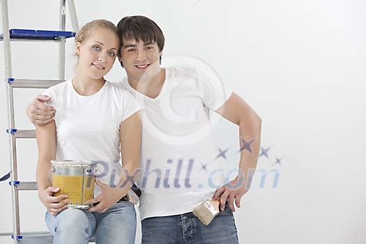Couple posing with paint can and a brush Couple posing with paint can and a brush