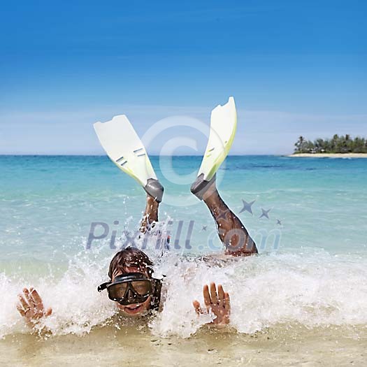 Man in small waves on the beach with snorkeling equipment Man in small waves on the beach with snorkeling equipment