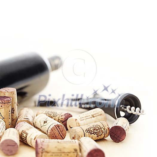Red wine bottle, corkscrew and corks in shallow focus Red wine bottle, corkscrew and corks in shallow focus