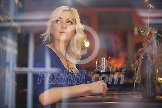 Woman looking out of window and having a glass of wine Woman looking out of window and having a glass of wine