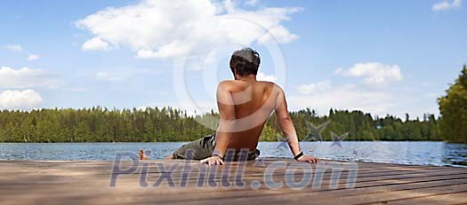 Man sitting on a dock paddling wiht his feet in the lake Man sitting on a dock paddling wiht his feet in the lake