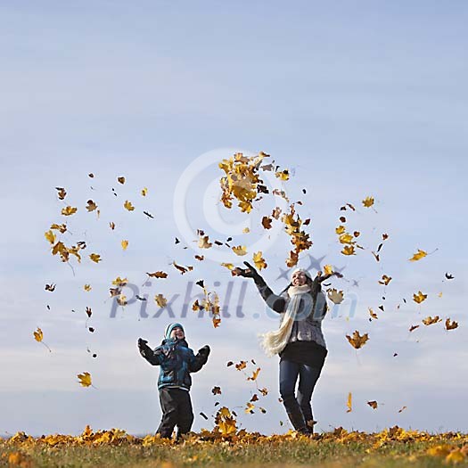 Mother and son throwing autumn leaves up in the sky Mother and son throwing autumn leaves up in the sky