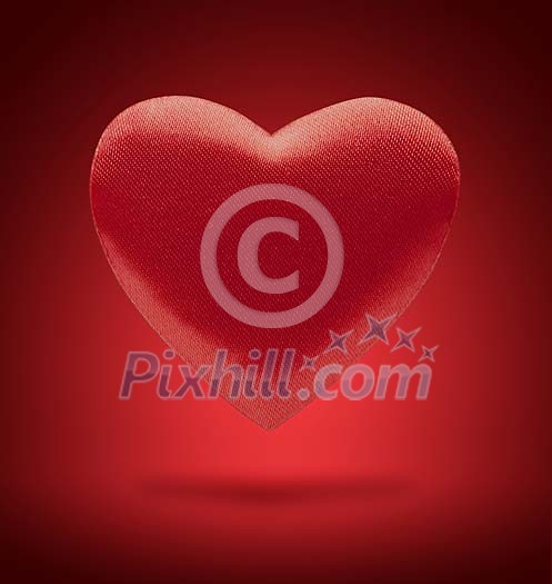 Red heart floating on red background Red heart floating on red background